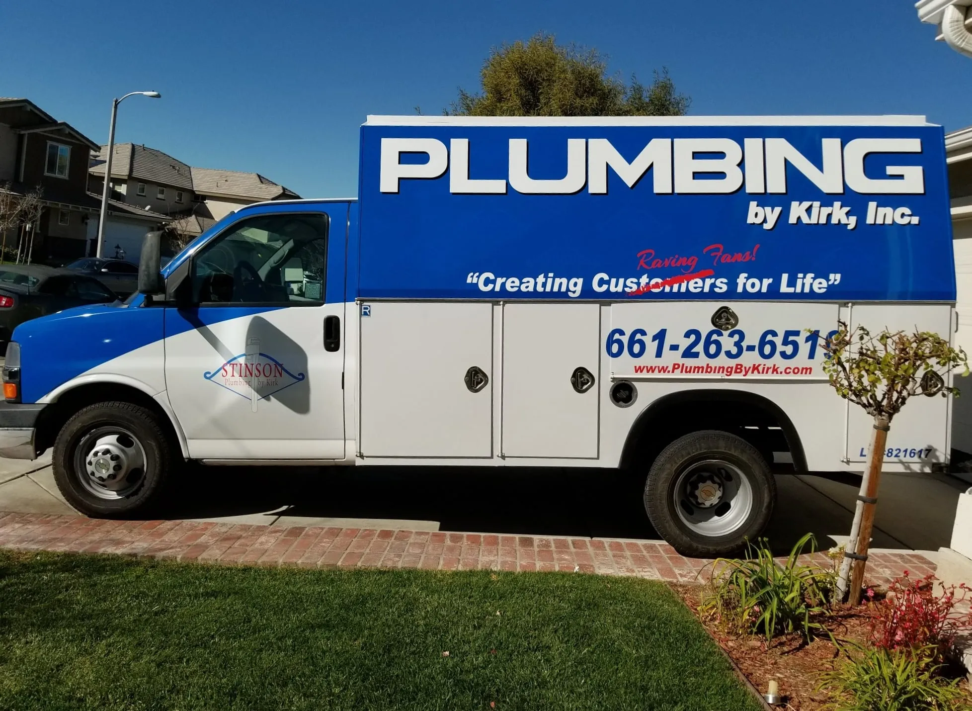 A Plumbing by Kirk service truck parked outside a home