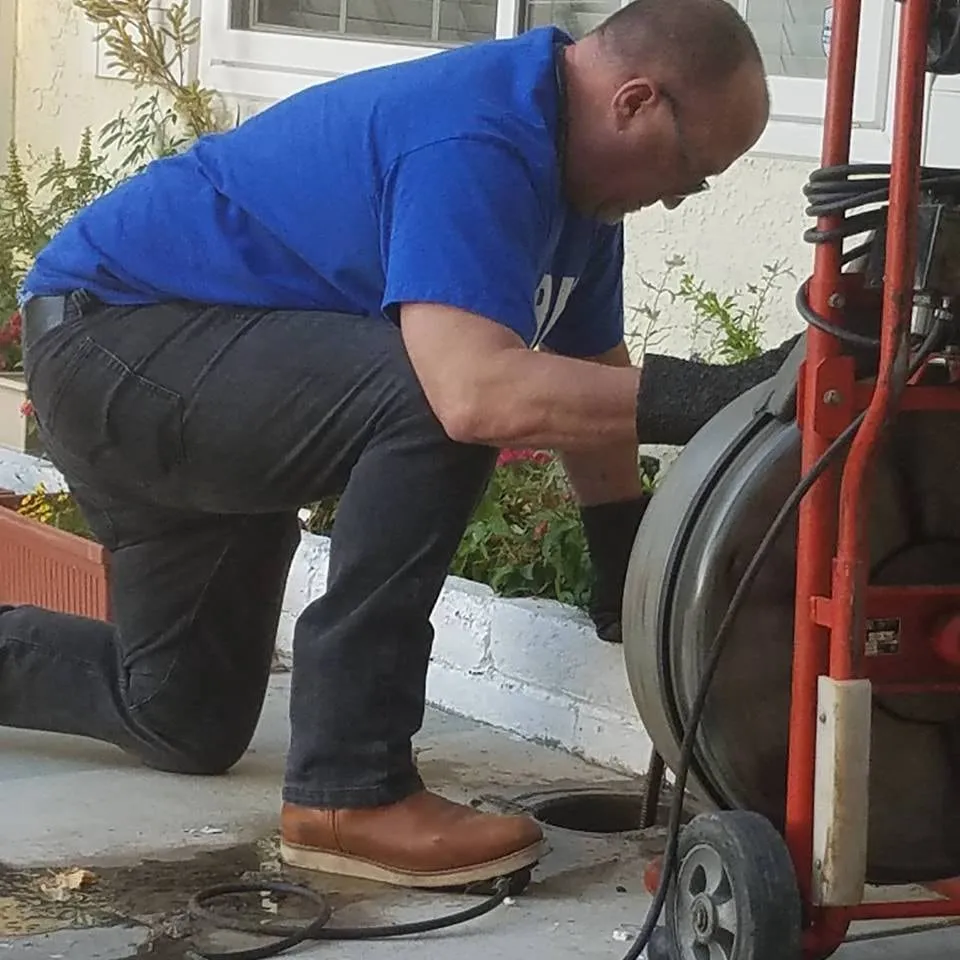 A Plumbing by Kirk plumber running a drain cable machine at an outdoor clean-out