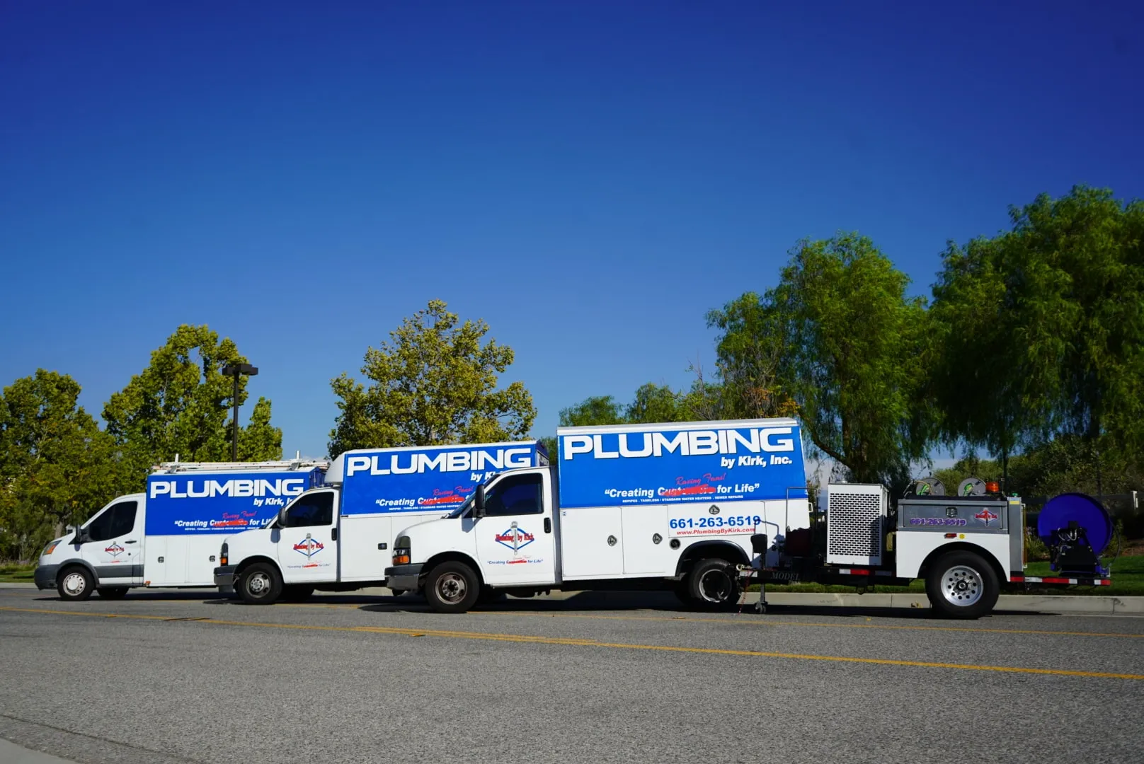 Three Plumbing by Kirk service trucks parked in a row