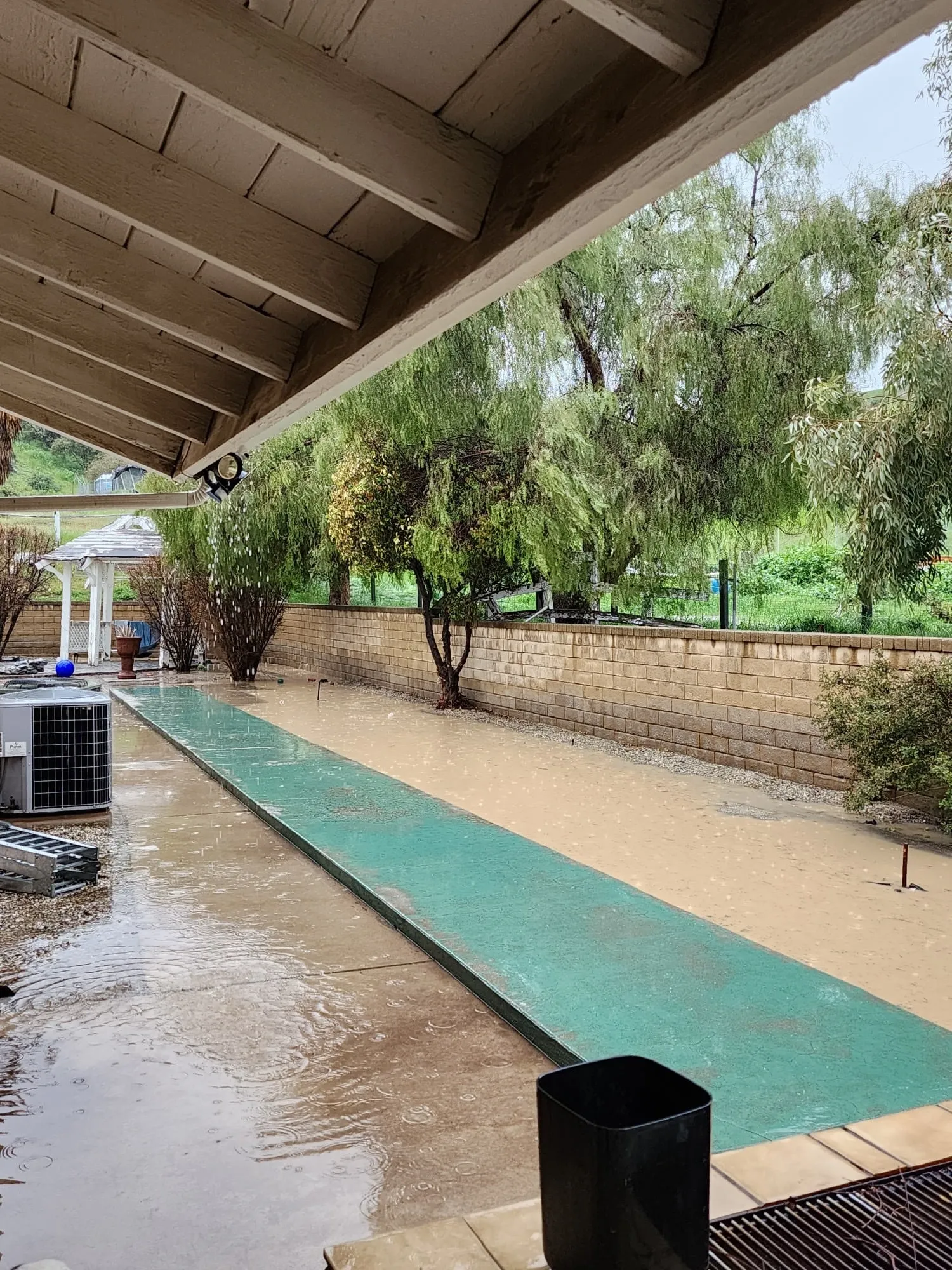 Water pooled along a side-yard walkway beside a house