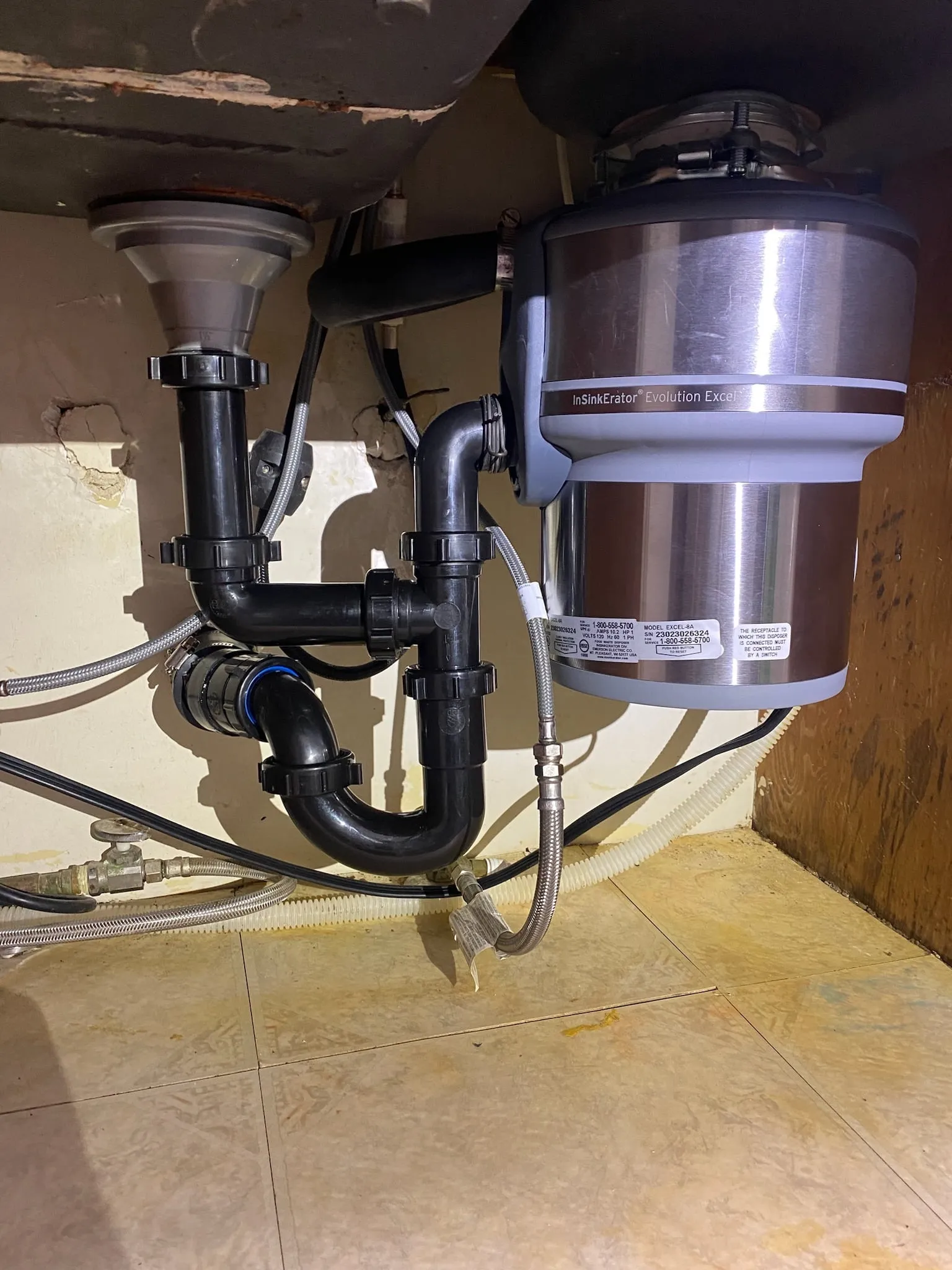 A garbage disposal and new drain lines installed under a kitchen sink